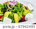 Food on a plate next to a Greek salad 67942493