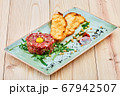 A beef tartare sitting on top of a wooden cutting board 67942507
