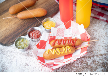corn dog with ketchup and yellow mustard 67942687