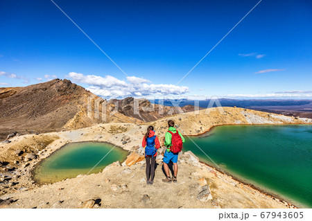 New Zealand popular tourist hiking hike in Tongariro Alpine Crossing National Park. Tramping trampers couple hikers walking on famous destination in NZ New Zealand popular tourist hiking hike in Tongariro Alpine Crossing National Park. Tramping trampers couple hikers walking on famous destination in NZ 67943605