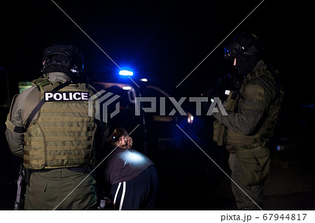 A police officer puts handcuffs on a criminal's...の写真素材