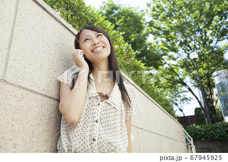 壁にもたれて電話する女性 壁にもたれて電話する女性 67945925