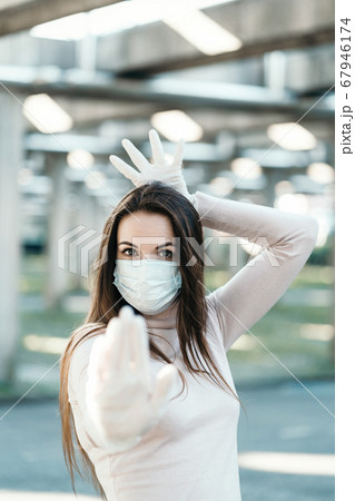 Young girl in medical mask and gloves shows stop sign Young girl in medical mask and gloves shows stop sign 67946174