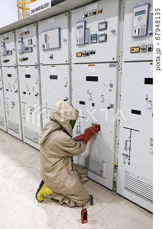 The operator wear arc flash suit, electrical safety gloves and high voltage insulating boots to open power compartment door for rack out circuit breaker form switchgear 67948135