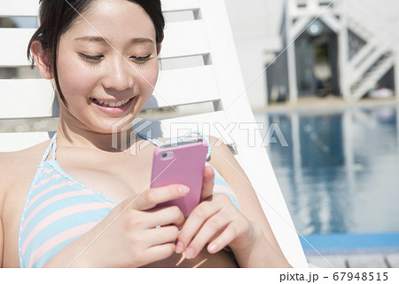携帯メールを見る水着姿の女性の写真素材