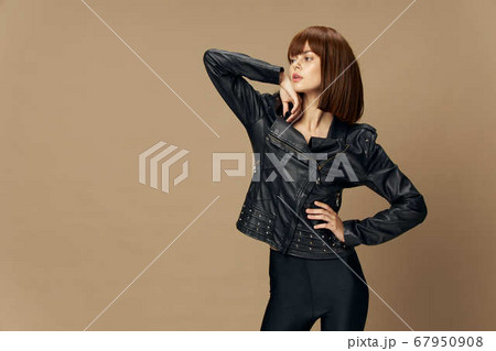 Young beautiful woman posing on a beige background in the studio in a black leather jacket Young beautiful woman posing on a beige background in the studio in a black leather jacket 67950908
