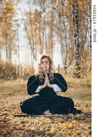 European woman with a katana in a kimono. the girl trains martial arts. a woman in the autumn forest. a warrior with a cold weapon in his hands 67950934