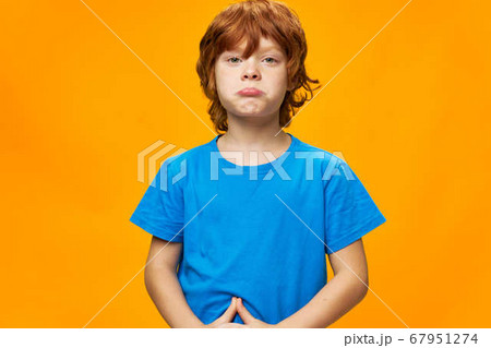 redhead boy The offended child pouted his lips blue t-shirt yellow background redhead boy The offended child pouted his lips blue t-shirt yellow background 67951274