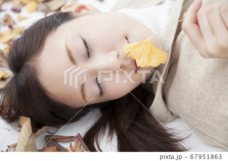 落ち葉に寝転ぶ女性 67951863