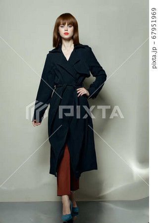 a pretty woman in trousers and in a black coat. 67951969