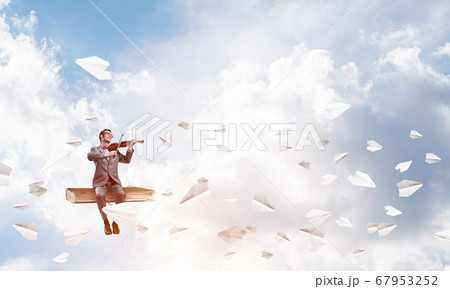 Handsome violinist play his melody and paper planes fly around Handsome violinist play his melody and paper planes fly around 67953252