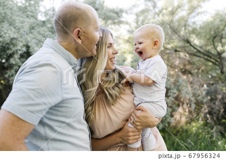 Happy parents with baby son laughing in garden Happy parents with baby son laughing in garden 67956324
