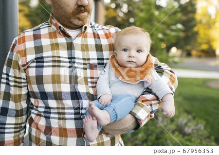 Outdoor portrait of baby boy carried by father 67956353