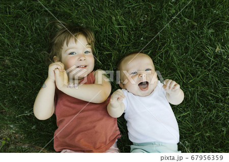 Portrait of happy siblings lying in grass 67956359