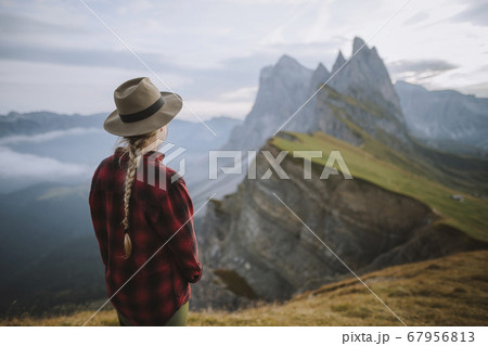 Italy, Dolomite Alps, Seceda mountain, Woman looking at scenic view of Seceda mountain in Dolomites at sunrise Italy, Dolomite Alps, Seceda mountain, Woman looking at scenic view of Seceda mountain in Dolomites at sunrise 67956813