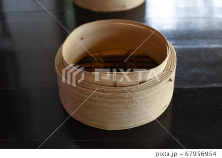 A Cylindrical wooden basket for adding dim sum on dark brown table A Cylindrical wooden basket for adding dim sum on dark brown table 67956954