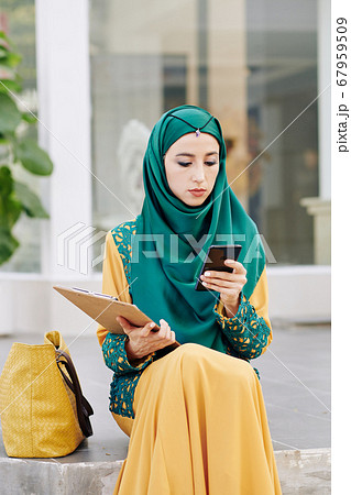 Muslim businesswoman checking phone 67959509