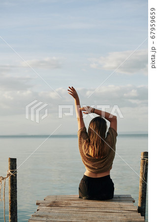 Woman stretching on pier Woman stretching on pier 67959659