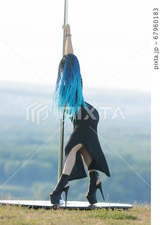 Woman with blue braids on high heels holding by the pole outdoors Woman with blue braids on high heels holding by the pole outdoors 67960183