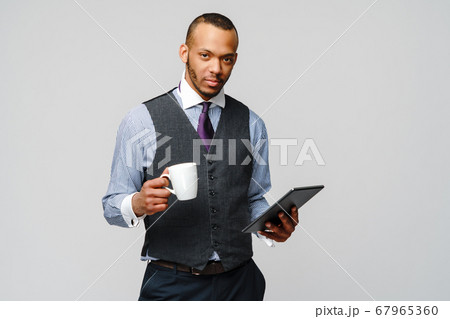 professional african-american business man holding tablet pc and cup of coffee 67965360