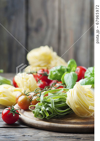 Raw pasta, tomato and basil on the wooden table Raw pasta, tomato and basil on the wooden table 67965972