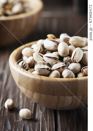 Salt pistachio nuts in the wooden bowl Salt pistachio nuts in the wooden bowl 67966472