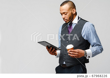 professional african-american business man holding tablet pc and cup of coffee professional african-american business man holding tablet pc and cup of coffee 67968226