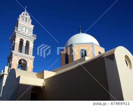 St John the Baptist Cathedral is a Roman Catholic church in Fira (Thira), Santorini, Greece.  It is one of many churches in Fira, Santorini.  The church has a white dome against a blue sky. Santorini. 67968411
