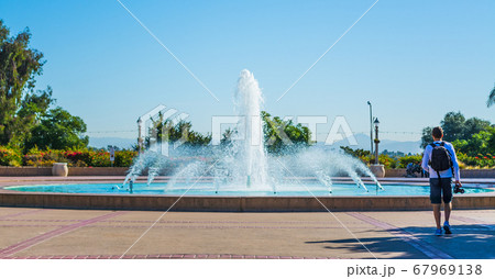 Photographer walking by a fountain in Balboa park 67969138