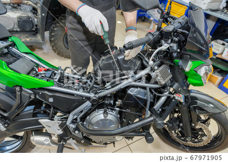 The master performs maintenance on the motorcycle. The master performs maintenance on the motorcycle. 67971905