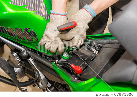 The master performs maintenance on the motorcycle. The master performs maintenance on the motorcycle. 67971906