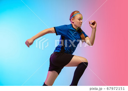 Female soccer, football player training in action isolated on gradient studio background in neon light Female soccer, football player training in action isolated on gradient studio background in neon light 67972151
