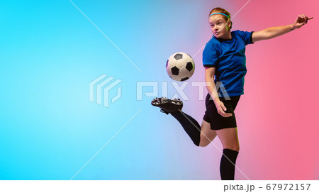 Female soccer, football player training in action isolated on gradient studio background in neon light Female soccer, football player training in action isolated on gradient studio background in neon light 67972157