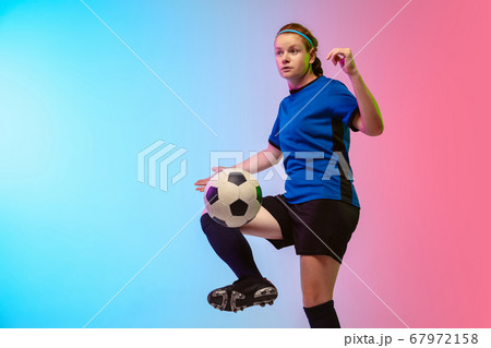 Female soccer, football player training in action isolated on gradient studio background in neon light Female soccer, football player training in action isolated on gradient studio background in neon light 67972158