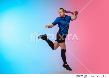 Female soccer, football player training in action isolated on gradient studio background in neon light Female soccer, football player training in action isolated on gradient studio background in neon light 67972215