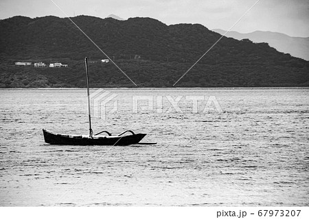 沖縄の海に浮かぶ小さな船の白黒写真 67973207