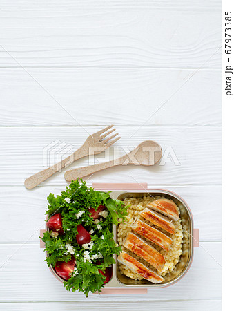 Lunch box full of delicious healthy food: salad, coucous and grilled chicken top view on white wooden table with copy space 67973385