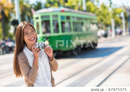 Asian woman tourist -city street lifestyle, famous tramway cable car system in San Francisco city, California during summer vacation. Travel fun taking pictures with vintage camera. 67975375