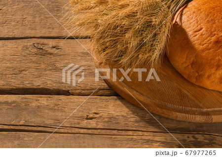 Whole loaf of bread and wheat ears on wooden background. 67977265