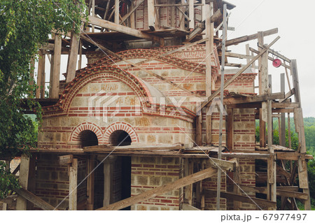 Construction of a new church in a modern style. Scaffolding around the white walls of the church. New project. 67977497