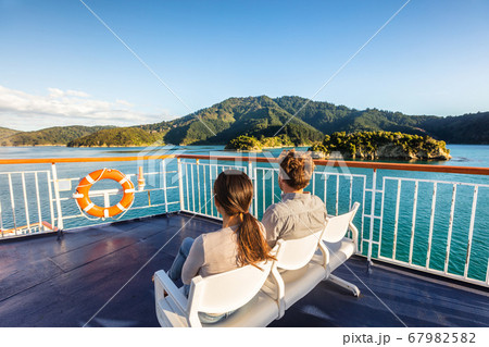 New Zealand cruise travel passengers enjoying nature view of ferry boat cruising in Marlborough sounds trip from Picton to Wellington, Cook strait. Couple tourists sitting outside on deck. 67982582