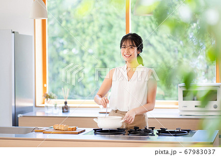 キッチンで料理をする若い女性の写真素材