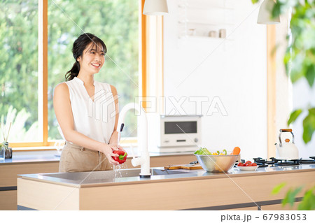 明るいキッチンで料理をする若い女性 明るいキッチンで料理をする若い女性 67983053