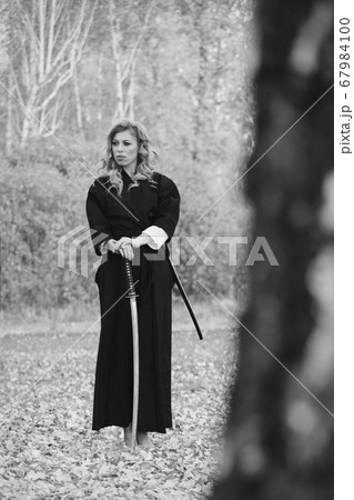 European woman with a katana in a kimono. the girl trains martial arts. a woman in the autumn forest. a warrior with a cold weapon in his hands 67984100