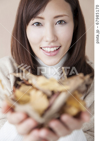 落ち葉を持つ女性 67985170