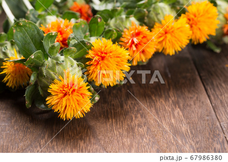 焦げ茶色のテーブルの上の紅花の花々のアップ 67986380