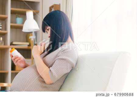 サプリメントを摂取する妊婦　考える　悩む　注意　コピースペース　 67990688