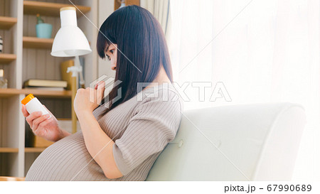 サプリメントを摂取する妊婦　考える　悩む　注意　コピースペース　16:9 67990689