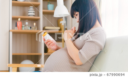 サプリメントを摂取する妊婦　考える　悩む　注意　コピースペース　16:9 67990694