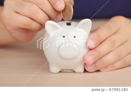 貯金箱にお金を入れる女性 67991190